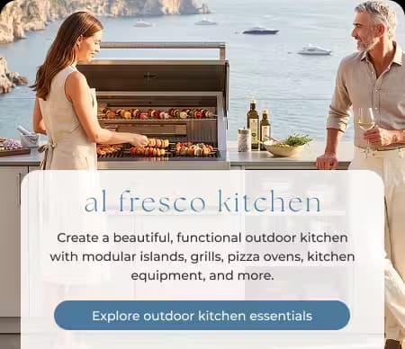 Two adults preparing a meal at a contemporary outdoor kitchen overlooking the ocean.