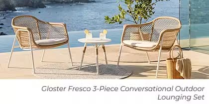 Two woven lounge chairs and a round side table create a cozy conversation area overlooking the ocean.