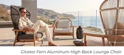 Man relaxing in a Gloster Fern high-back lounge chair on a luxury oceanfront patio with coastal views.