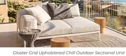 Modern, light grey sectional sofa with accent tables and pillows on a coastal balcony overlooking the ocean.